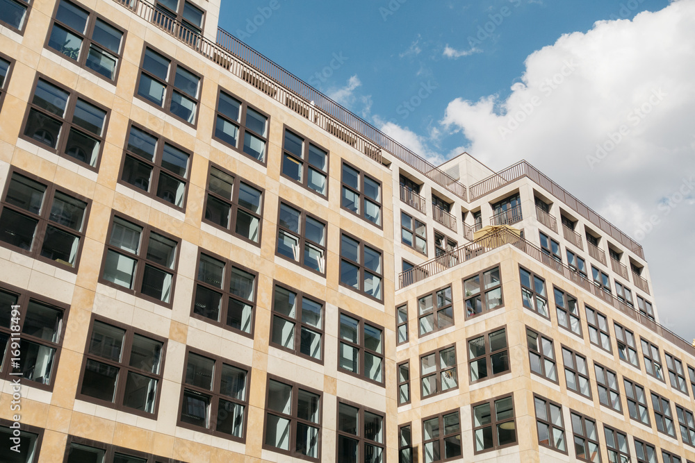 block formed office building with marble facade and clouds in the background