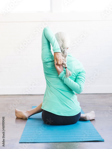 Senior woman practicing yoga on mat photo