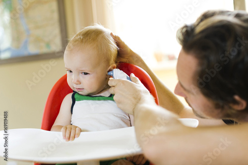 Father measuring son's (12-17 months) temperature photo