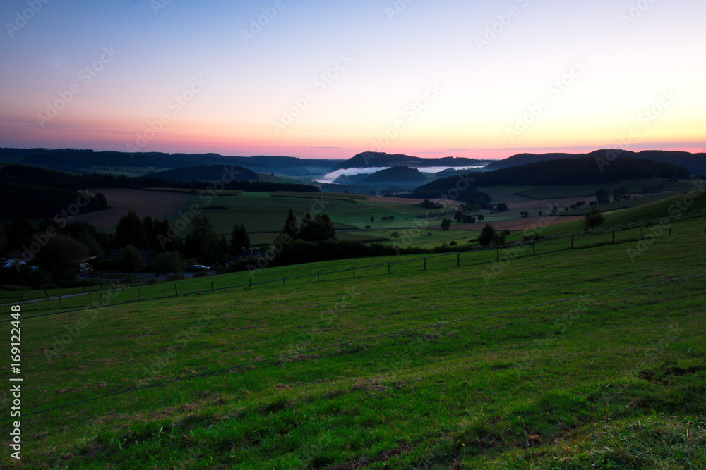 Landschaft bei Sonnenaufgang mit Nebelbank im Tal