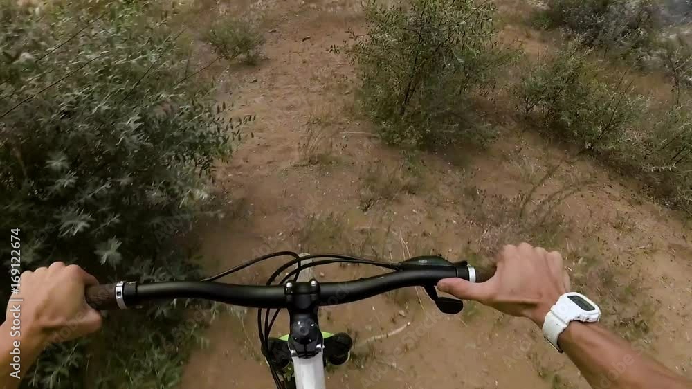 The cyclist slides down from the sand hill, the first person view The cyclist slides down from the sand hill, the first person view