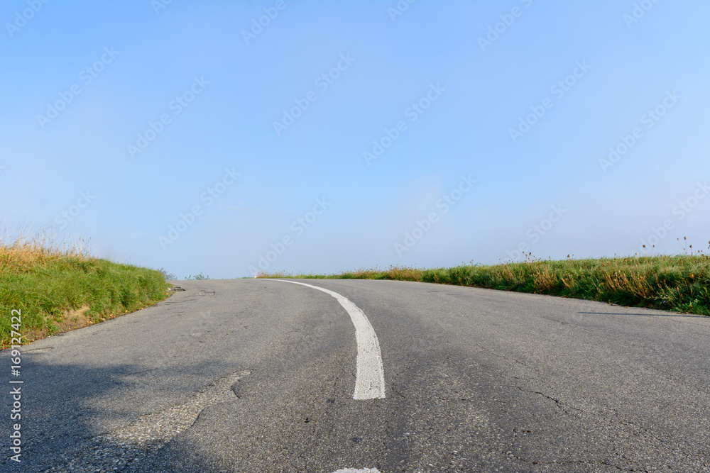 Fototapeta premium Strasse mit kurve und blauem Himmel
