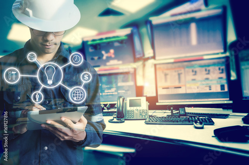 Double exposure of Engineer or Technician man with business industrial tool icons while using tablet with monitor of computers room  for oil and gas industrial business concept