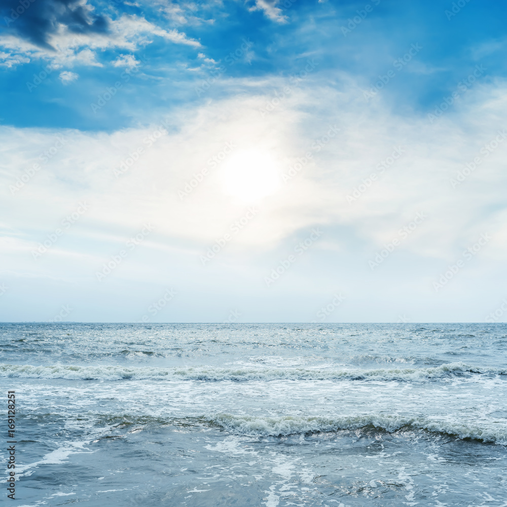 low sun in sunset over blue sea with waves