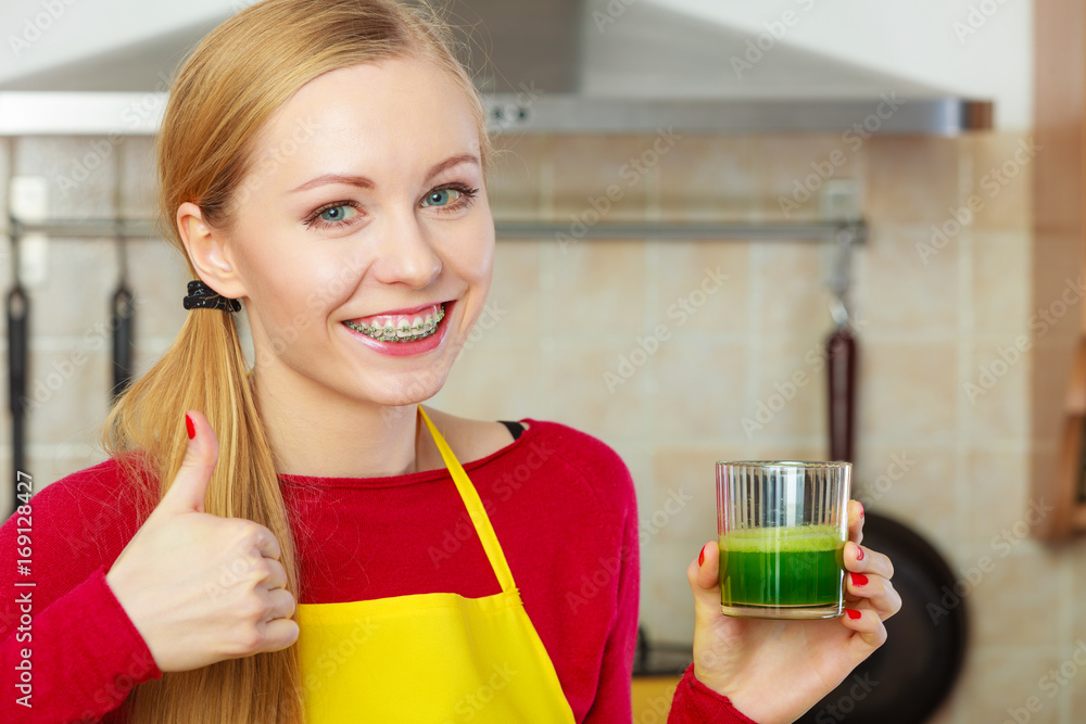 Woman in kitchen holding vegetable smoothie juice Woman in kitchen holding vegetable smoothie juice