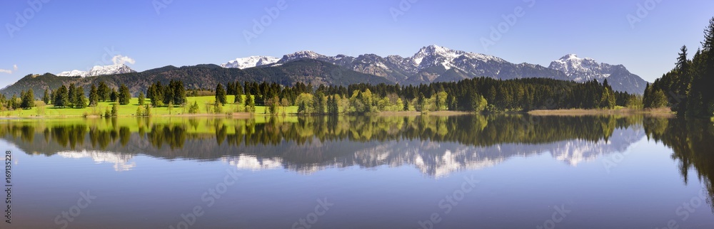 Panorama Landschaft in Bayern mit Spiegelung der Berge im Forggensee