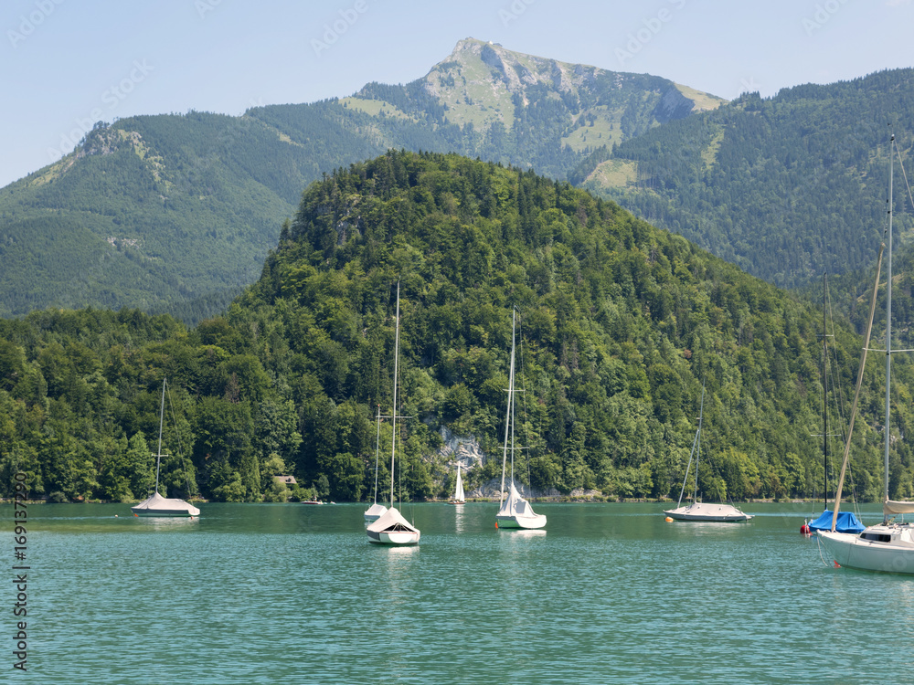 Naklejka premium Small harbor in Wolfgang see mountain lake. Anchored yachts, sunny weather. Summer sailing in Alps. Sport hiking landscape background.