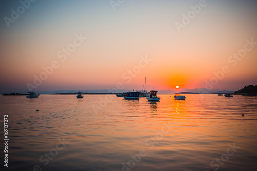 Boats in the sea at sunset in summer with mountains on background