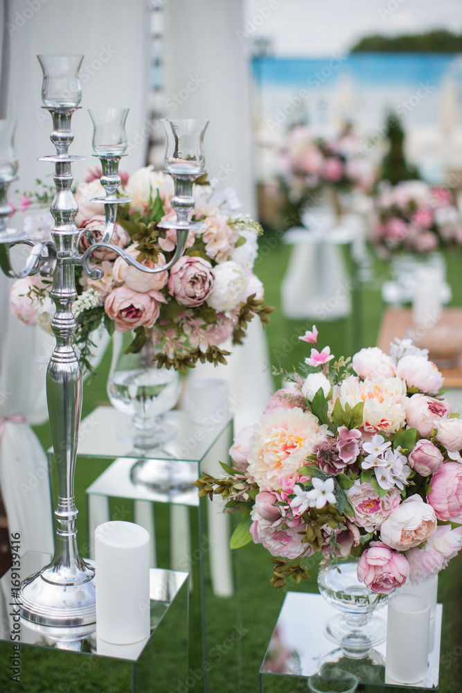 Outdoors wedding decoration with flower bouquets, candles and garlands