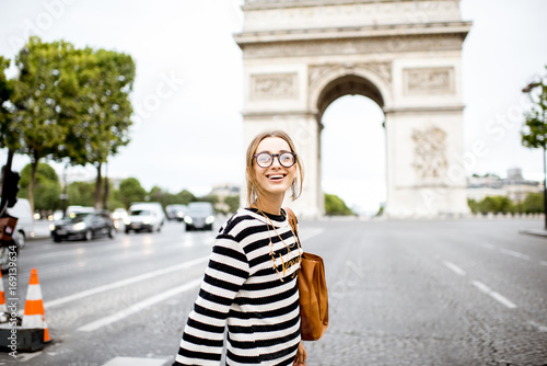 Young business woman in striped sweater crossing street near the famous triumpal arch in Paris