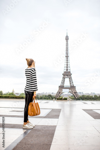 Lifestyle portrait of a stylish woman looking forward standing on the famous square with eiffel tower on the background in Paris © rh2010