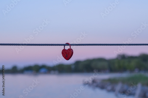 single red heart padlock hanging on a steel rope © Alexandra