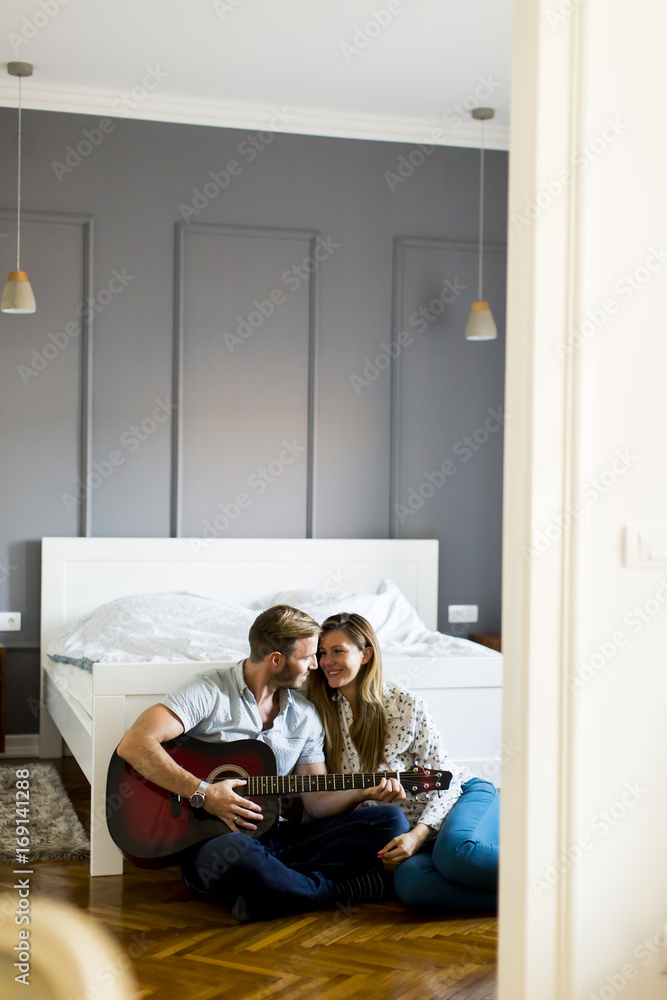 Obraz premium Romantic pair playing guitar on floor