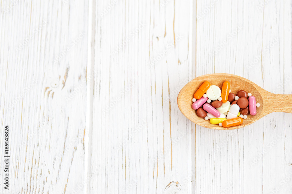 Many pills in a wooden spoon. Background. The concept of colds, illness, treatment, lifestyle. Many pills in a wooden spoon. Background. The concept of colds, illness, treatment, lifestyle.