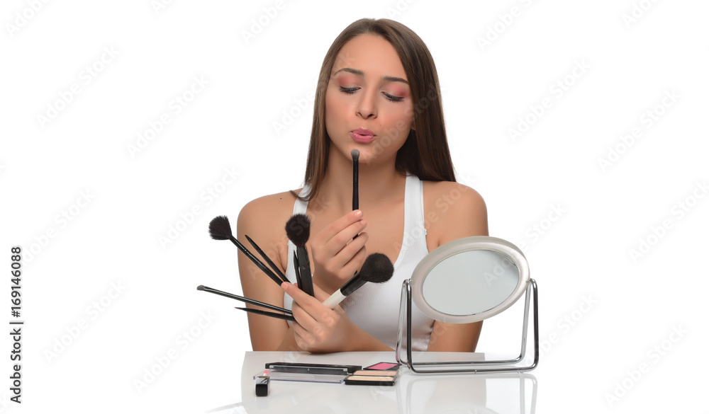  A young woman applying makeup on her face with a brush