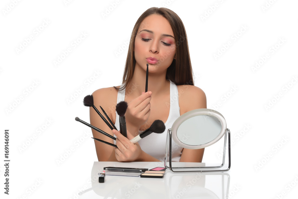  A young woman applying makeup on her face with a brush