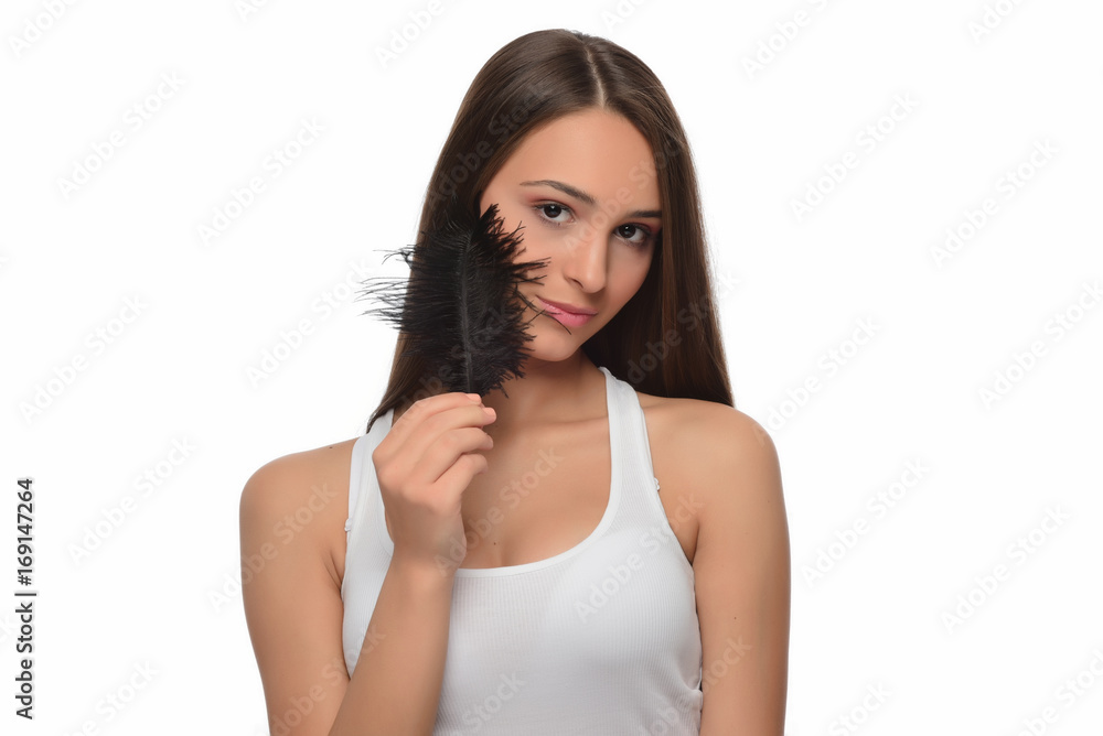 Beautiful young girl with large black feather. clean soft body products. Beauty Portrait. Woman Touching. Perfect Fresh Skin. Youth and Skin Care Concept. Studio shot. Isolated on blue background Beautiful young girl with large black feather. clean soft body products. Beauty Portrait. Woman Touching. Perfect Fresh Skin. Youth and Skin Care Concept. Studio shot. Isolated on blue background