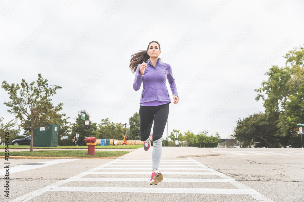 Woman jogging and crossing the road on zebra in Chicago Woman jogging and crossing the road on zebra in Chicago