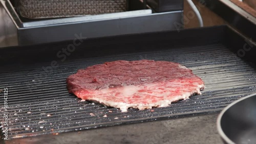 Hand of master chief using sunflower oil while cooking meat (grilling) for hamburger. photo