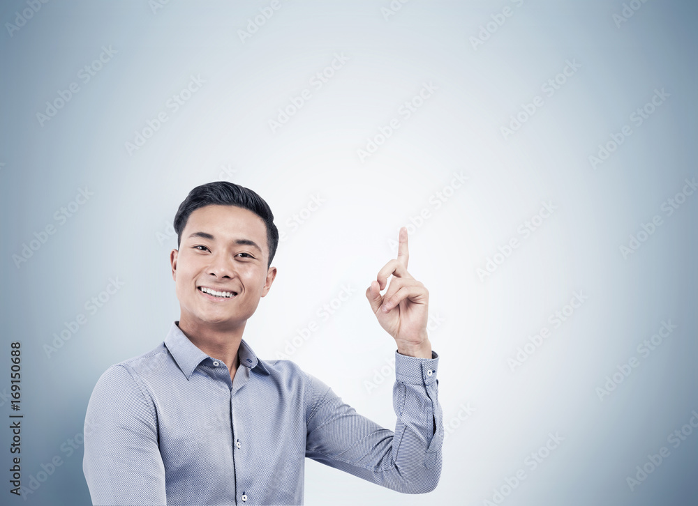 Portrait of cheerful Asian businessman pointing up Portrait of cheerful Asian businessman pointing up