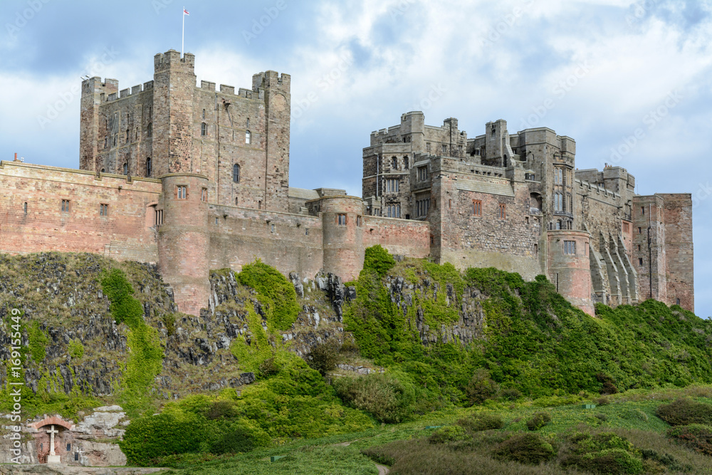 Bamburgh Castle on top of a green hill with blue sky