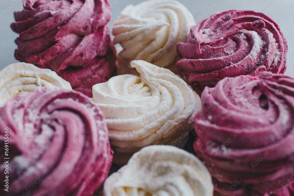 White mango and pink blueberry marshmallows or zephyr with sugar powder on a table. Homemade sweet. White mango and pink blueberry marshmallows or zephyr with sugar powder on a table. Homemade sweet.