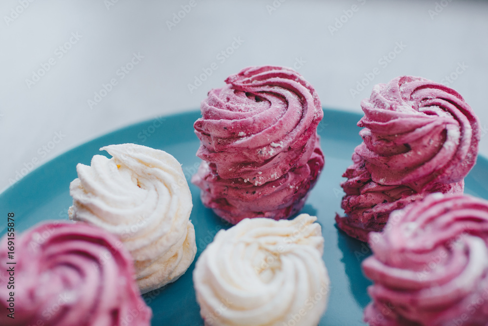 White mango and pink blueberry marshmallows or zephyr with sugar powder on a blue plate. Homemade sweet. White mango and pink blueberry marshmallows or zephyr with sugar powder on a blue plate. Homemade sweet.