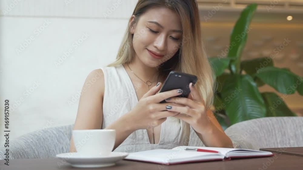 Woman using app on smartphone, drinking coffee, smiling, texting on mobile phone