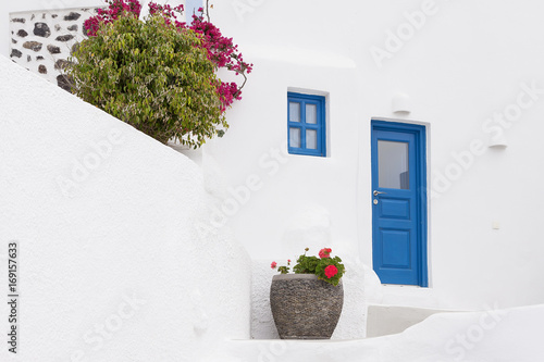 Fototapeta Naklejka Na Ścianę i Meble -  White house facade with blue door and flowers Santorini 