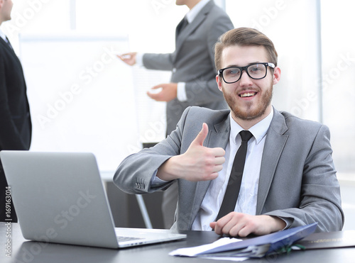 Manager sitting at his Desk and showing thumbs up