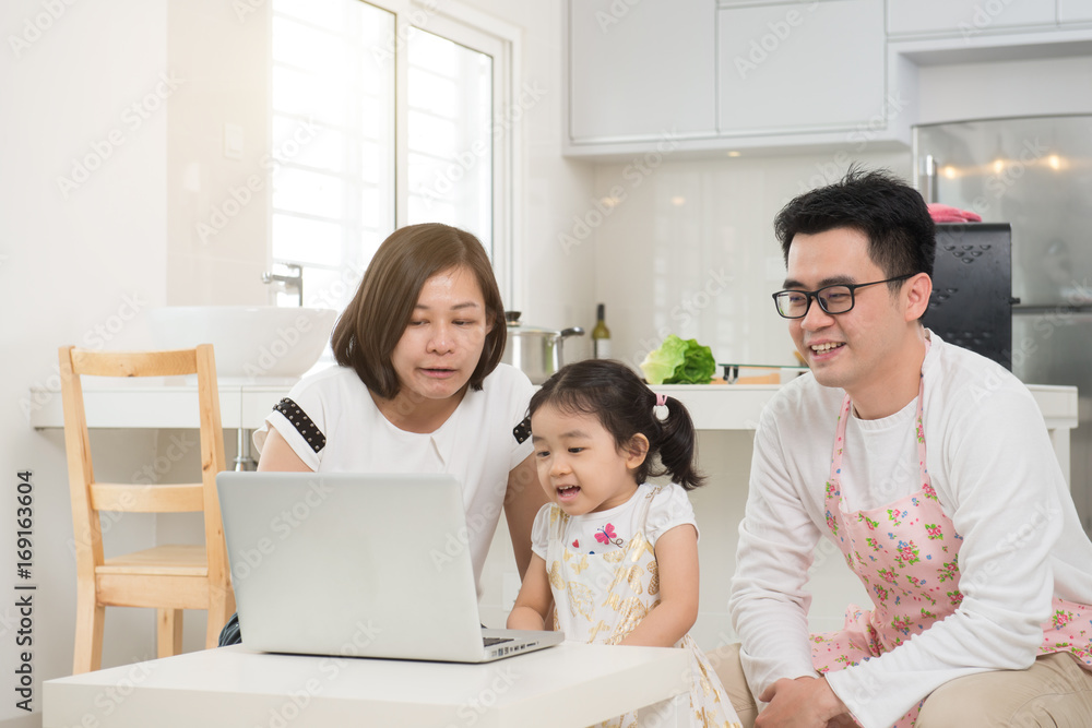 asian mother surfing internet with daughter while father cooking asian mother surfing internet with daughter while father cooking