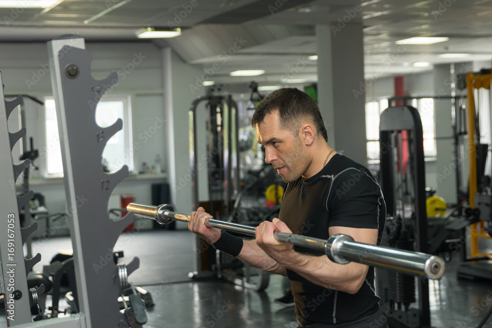 Strong man exercising with a barbell in a gym Strong man exercising with a barbell in a gym