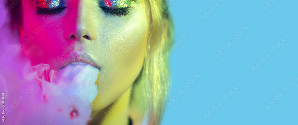 Fashion art portrait of beauty model woman in bright lights with colorful smoke. Smoking girl