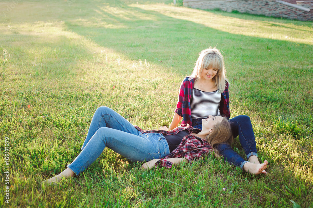 Two happy female friends playing and having fun in green grass Two happy female friends playing and having fun in green grass
