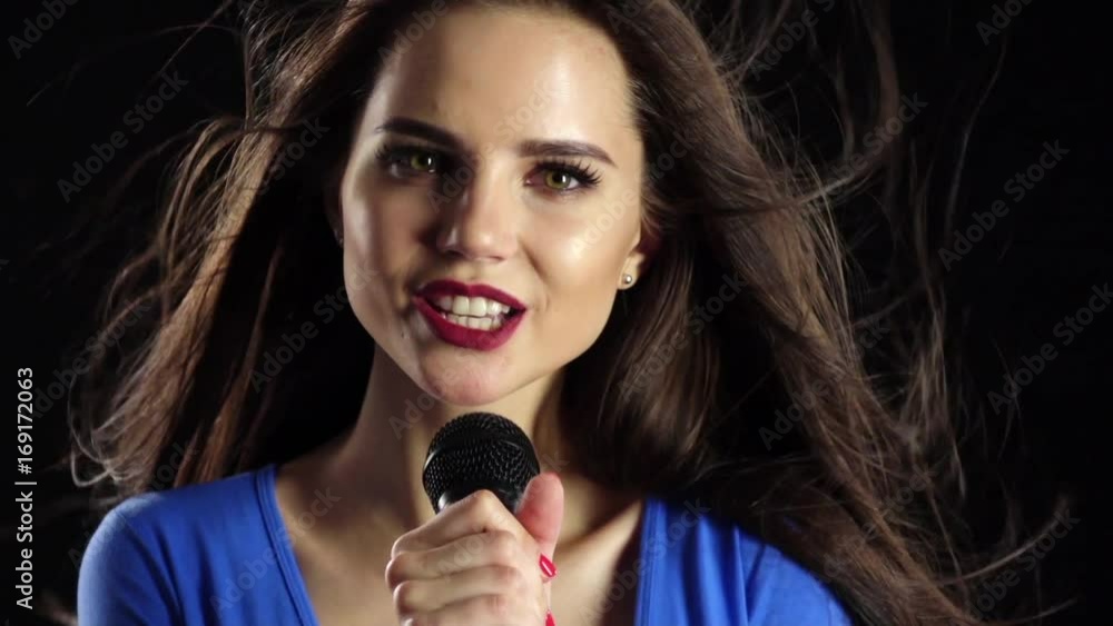 Girl is singing her hair fluttering in the wind. Black background. Slow motion Girl is singing her hair fluttering in the wind. Black background. Slow motion