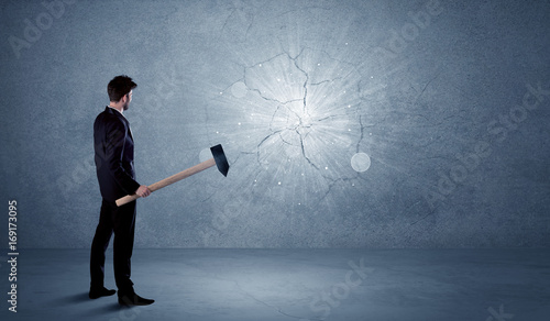 Business man hitting wall with a hammer