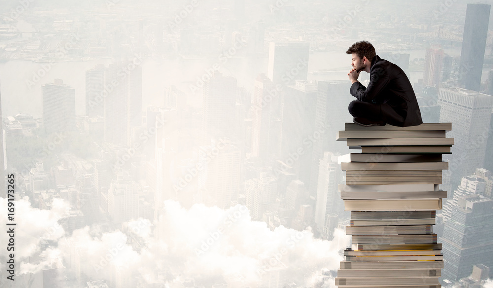 Student in city sitting on stack of books Student in city sitting on stack of books