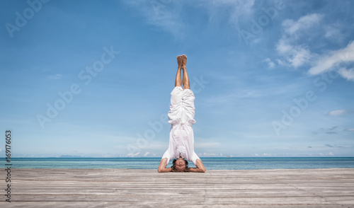 Foto Young man doing yoga exercise - headstand, on a beautiful tropical beach