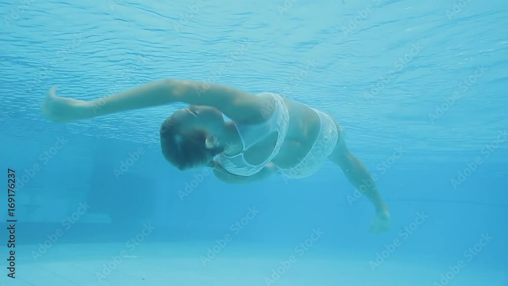 Young woman in swimsuit swimming underwater in swimming pool and spinning Young woman in swimsuit swimming underwater in swimming pool and spinning