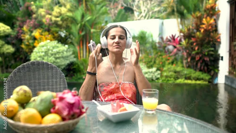 Attractive tanned music plays music on smartphone and listening it in exotic place, steadycam shot
Attractive tanned music plays music on smartphone and listening it in exotic place, steadycam shot
