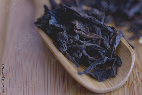 Black leaf tea in a wooden spoon