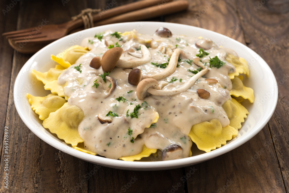 Plate of ravioli with cream sauce on wood table

