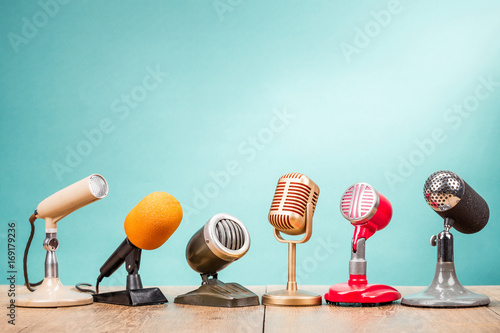 Retro old microphones for press conference or interview on table front gradient aquamarine background. Vintage old style filtered photo