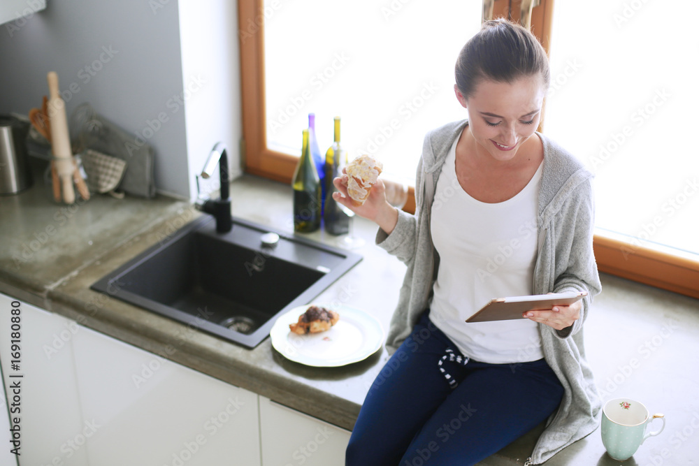 Beautiful young woman using a digital tablet in the kitchen. Beautiful young woman using a digital tablet in the kitchen.