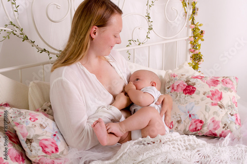 Obraz na płótnie Breastfeeding baby. Young mother holding her newborn child. Mom nursing baby. Woman and new born boy in white bedroom. w salonie
