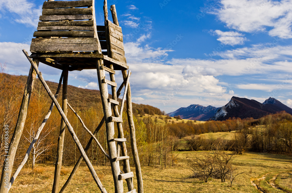 Meadow with hunting watchtower with mountain peaks in background, Homolje mountains landscape on a sunny day in early spring, east Serbia Meadow with hunting watchtower with mountain peaks in background, Homolje mountains landscape on a sunny day in early spring, east Serbia