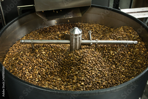 At coffee factory. Freshly roasted coffee beans in professional roasting machine