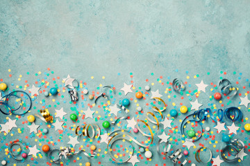 Holiday background decorated colorful confetti, star, candy and streamer on blue vintage table top view. Flat lay style. Festive border with copy space.