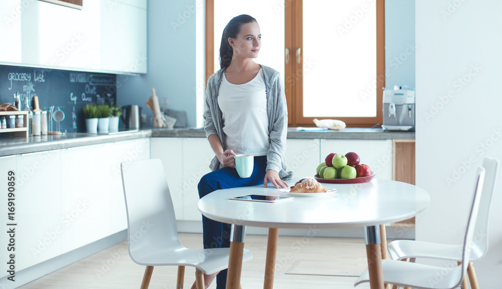 Happy woman drinking tea in the kitchen at home Happy woman drinking tea in the kitchen at home
