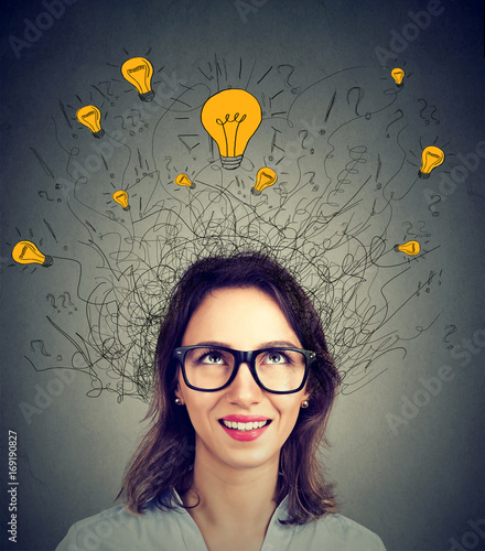 Young woman in glasses with many ideas light bulbs above head looking up